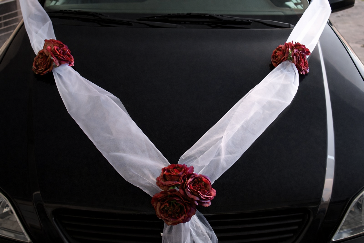 Svadobná výzdoba na auto s bielou stuhou a červenými ružičkami A 047